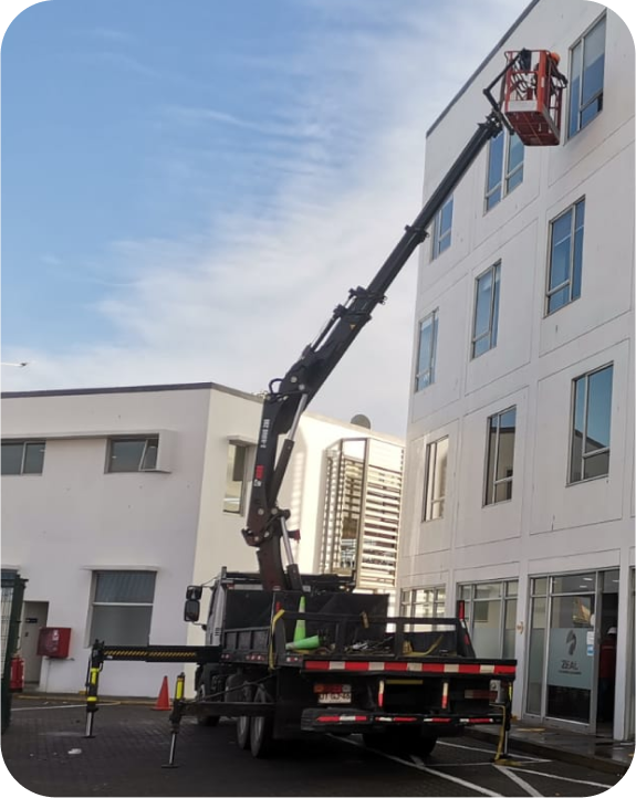 Hombre limpiando la fachada de un edificio con un brazo mecánico
